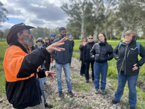 Man in high vis jacket speaking to group of people outdoors