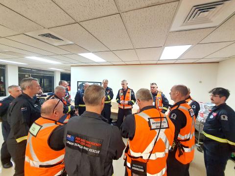 Group of emergency personnel all huddled in a circle inside a room